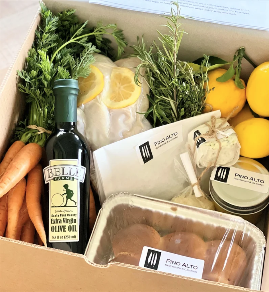 culinary market box filled with carrots, olive oil, bread, lemons